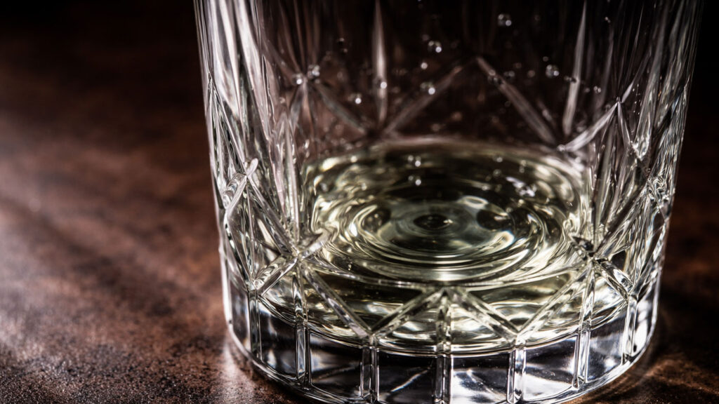 Close-up of a crystal glass rinsed with absinthe, leaving a thin aromatic layer inside.